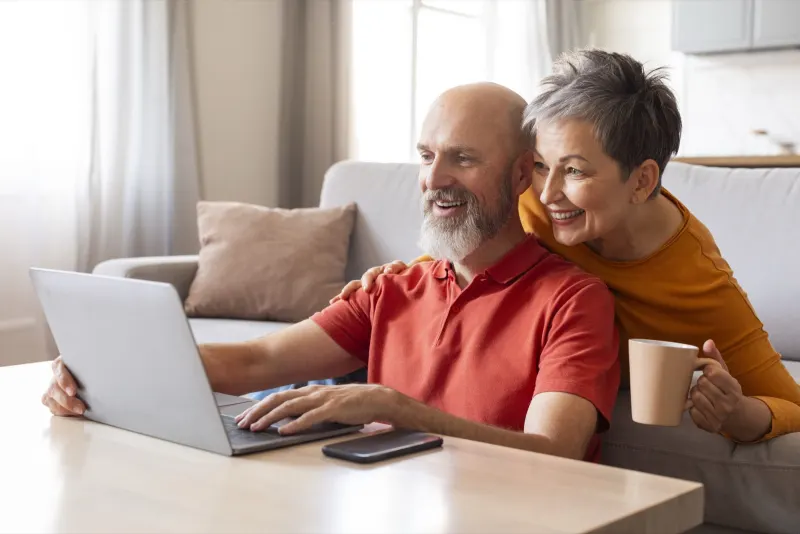 Twee oudere mensen kijken samen op een laptop